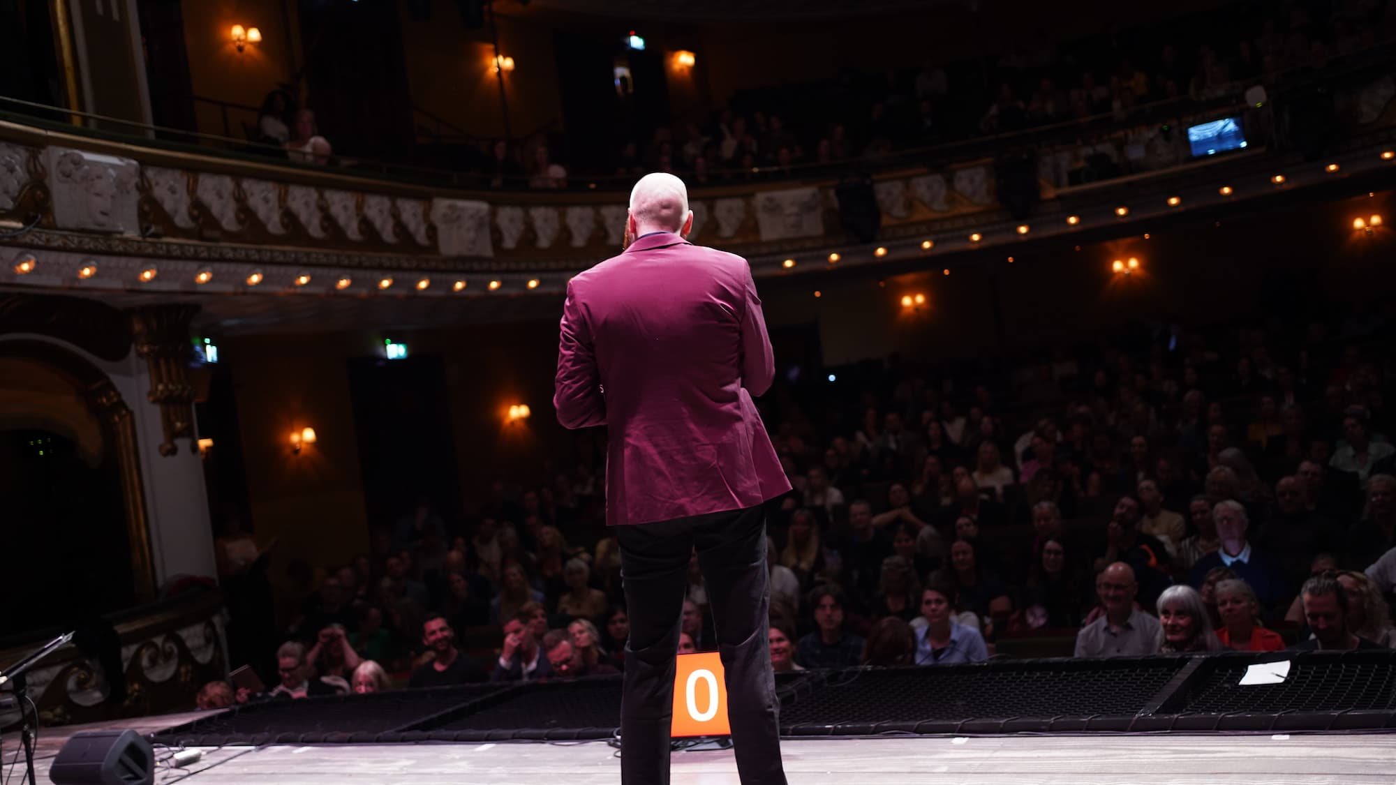 Eric Bergström föreläser på scen i en fullsatt teatersalong